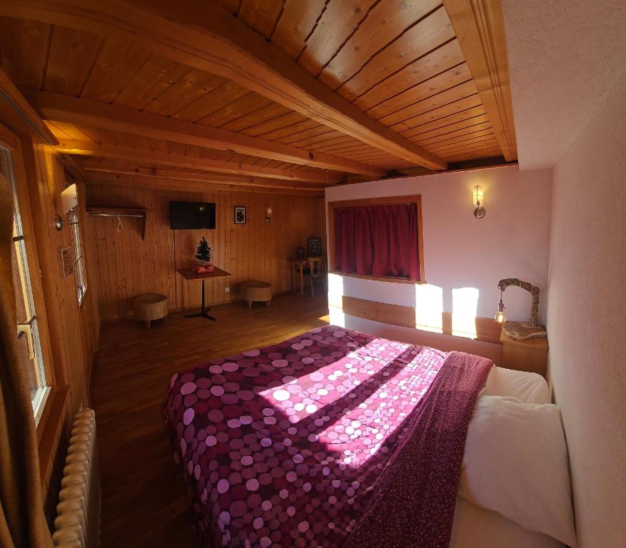 ein Schlafzimmer mit einem Bett mit einer lila Decke darauf in der Unterkunft L'Auberge de la Comballaz in La Comballaz