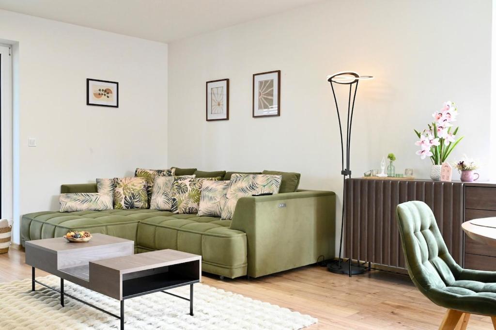a living room with a green couch and a table at Pool & Relax Mukařov in Srbín