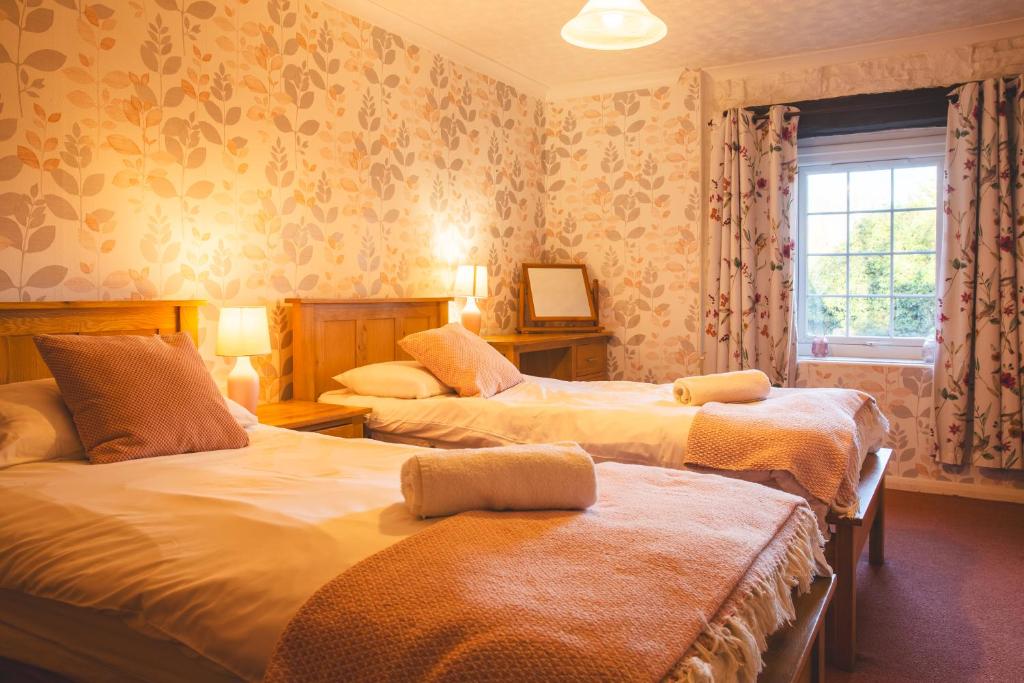 een slaapkamer met twee bedden en een raam bij Langriggs at Wetheral Cottages in Great Salkeld