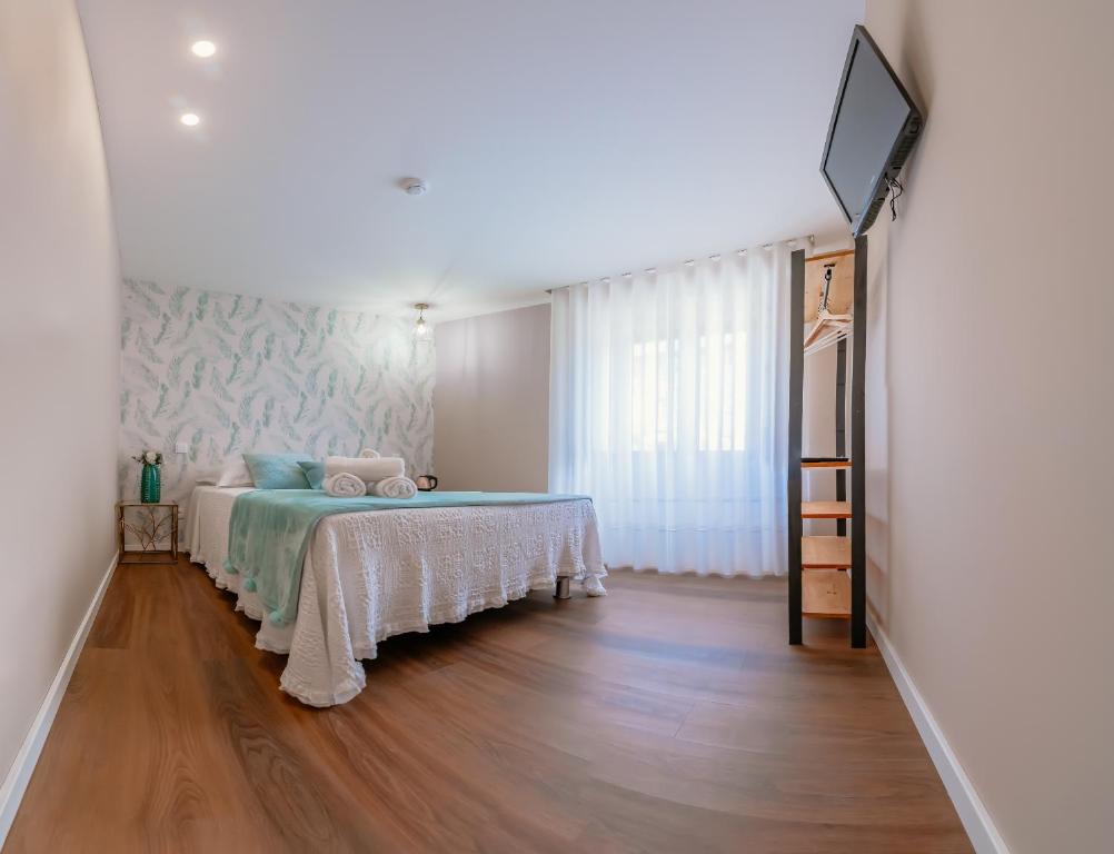 a bedroom with a bed and a flat screen tv at Blue House Ponte de Lima in Ponte de Lima