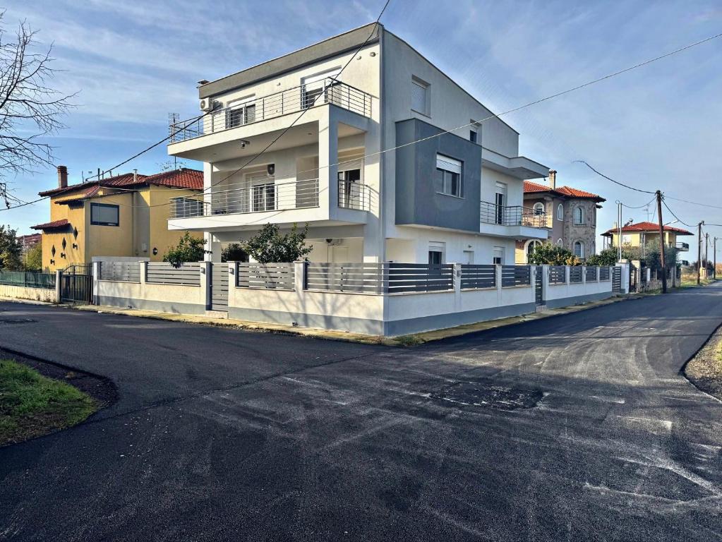 a large white house on the side of a street at Adoniss Apartmentss 2 in Paralia Dionysiou