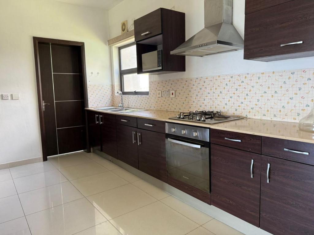 a kitchen with brown cabinets and a stove top oven at Le Meritt Appartments in Quatre Bornes
