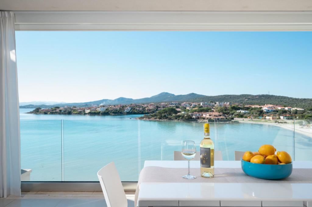 a table with a bottle of wine and a bowl of fruit at Appartamenti Aironi - Your House in Sardinia in Golfo Aranci