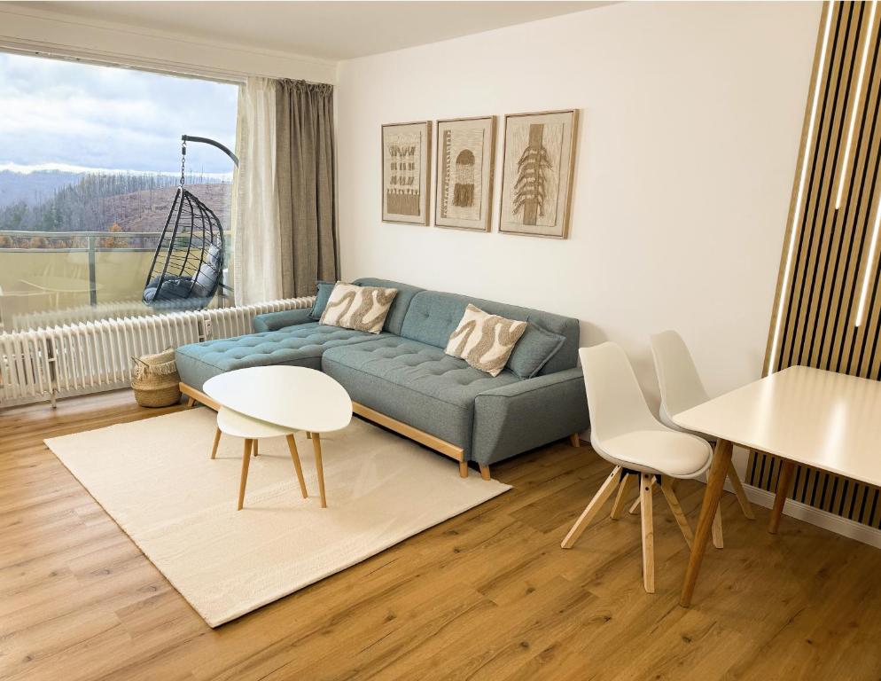 een woonkamer met een blauwe bank en een tafel en stoelen bij Neu! Hirschgrund 10 OG Panorama, Sauna, Pool in Braunlage