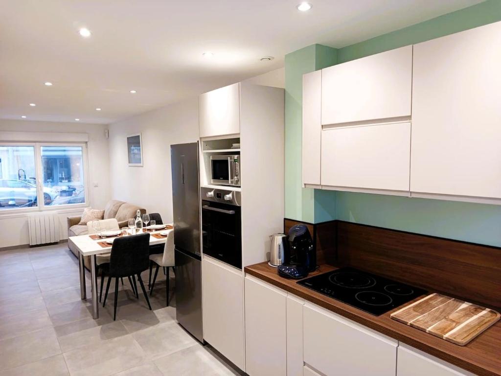 a kitchen with white cabinets and a table with a dining room at The Calais Beacon in Calais