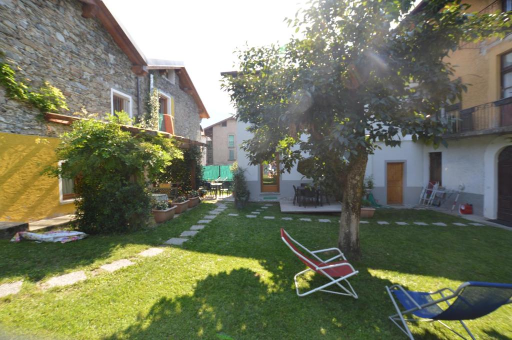 un patio con sillas, un árbol y un edificio en Piccola Corte, en Colico