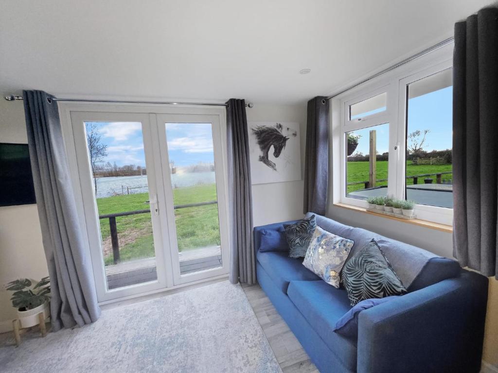 Meysey HamptonLakeview at The Hideaway的客厅设有蓝色的沙发和大窗户