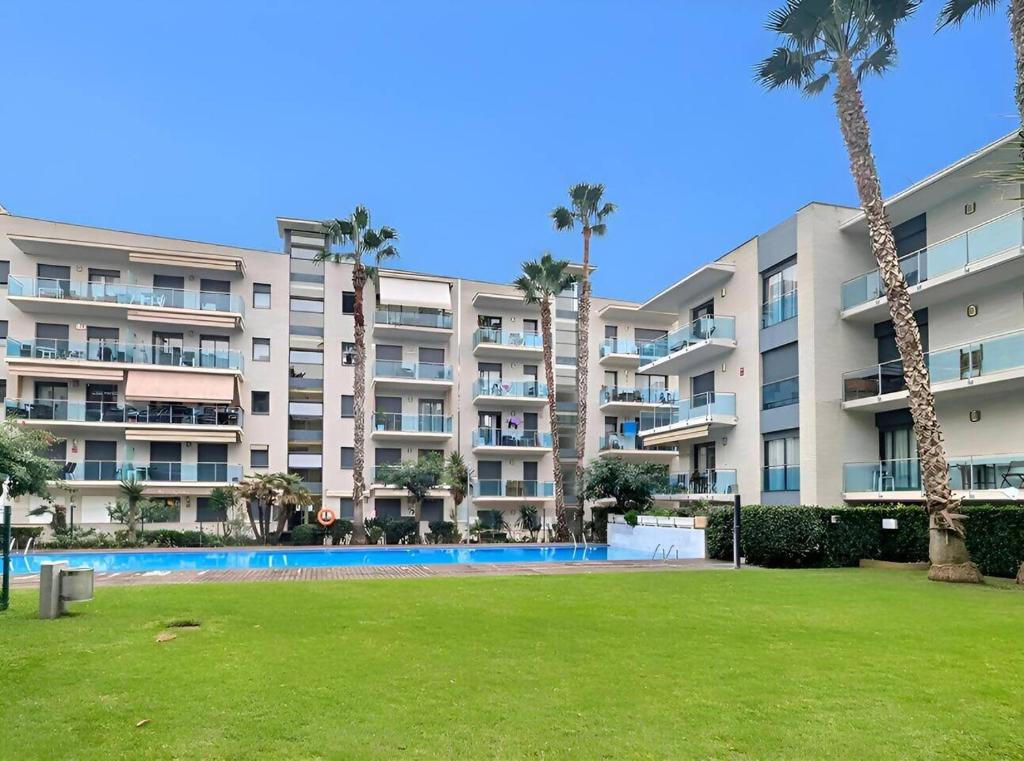 a large apartment building with a swimming pool and palm trees at Relax en Lloret con Gym y Piscina by Host&Joy in Lloret de Mar