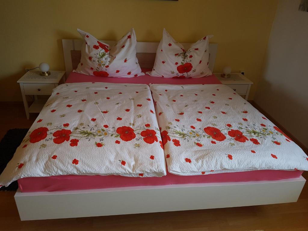 a bed with red flowers on it with two pillows at Haus zur Sonne in Sankt Urban