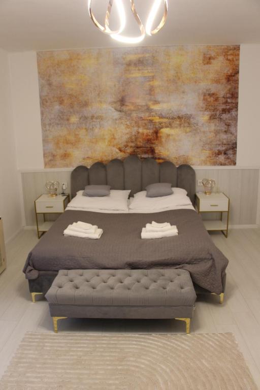 a bedroom with a bed and a painting on the wall at GrandPa Delux in Miskolc