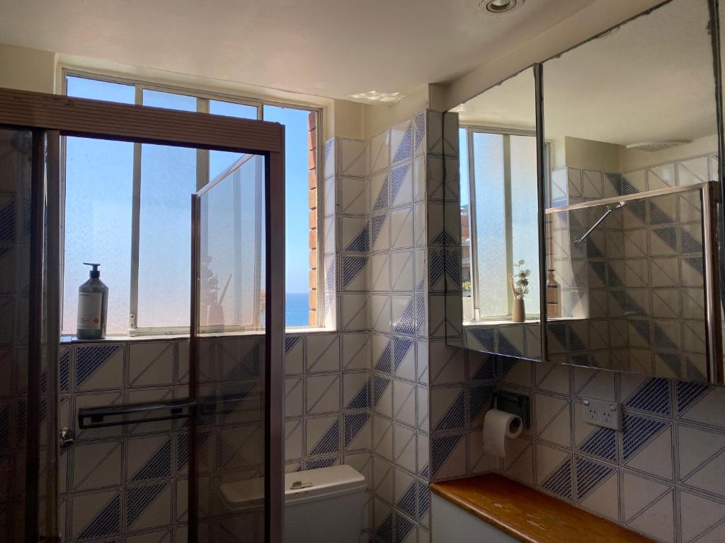 een badkamer met douche en toilet en een raam bij Beach & Ocean View Apartments Tamarama in Sydney