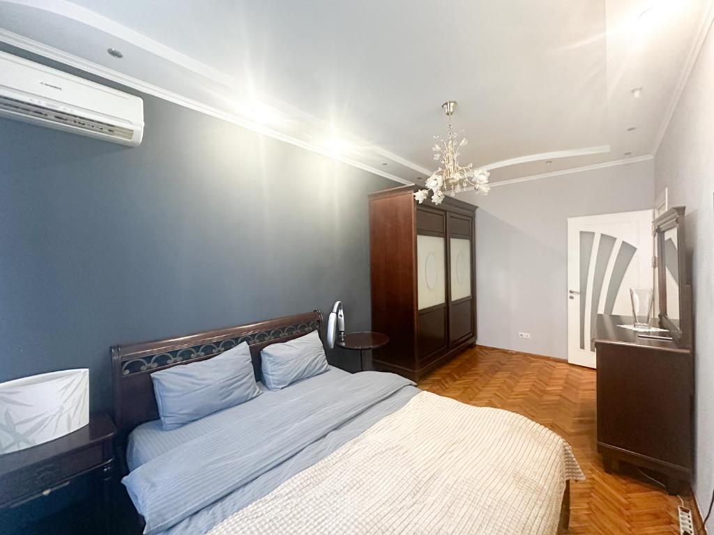 um quarto com uma cama com lençóis brancos e um lustre em Central City Puskin Street em Chişinău