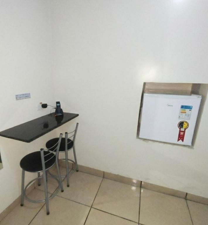 una stanza con un bancone, due sedie e una lavagna bianca di Motel Suítes a Panorama