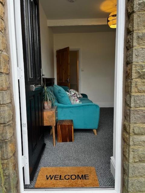 a living room with a blue couch and a doorway at Delightful 1 Bedroom Cottage in Buxton