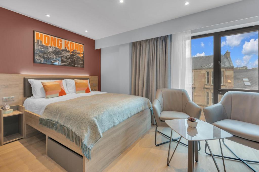 a bedroom with a bed and two chairs and a window at The Bonnie in Glasgow