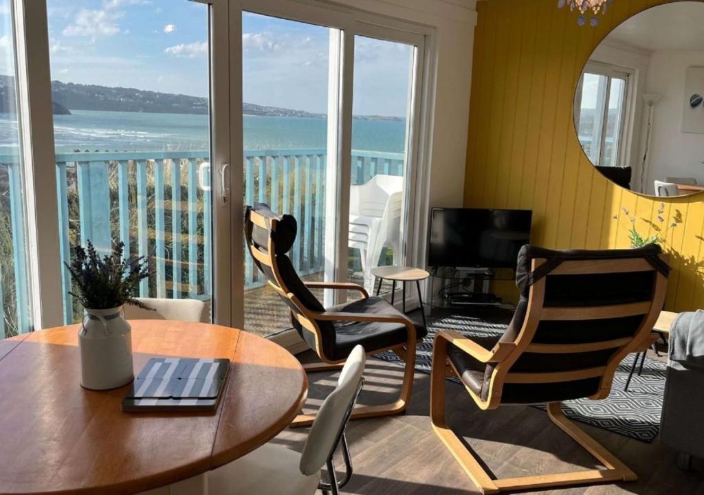ein Wohnzimmer mit Tisch und Stühlen und einem Balkon in der Unterkunft D39 St Margarets, Riviere Towans in Hayle