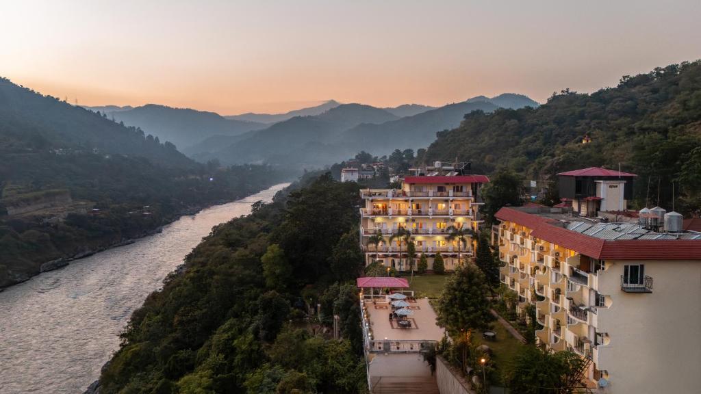 a group of buildings next to a river with mountains at juSTa Riverside Resort Srinagar in Devaprayāg
