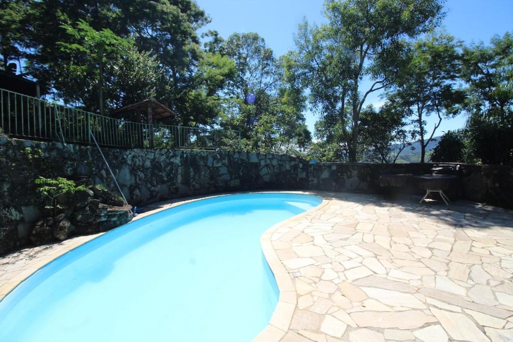 einen Pool neben einer Steinmauer in der Unterkunft Chácara in Mairiporã - São Paulo in Mairiporã