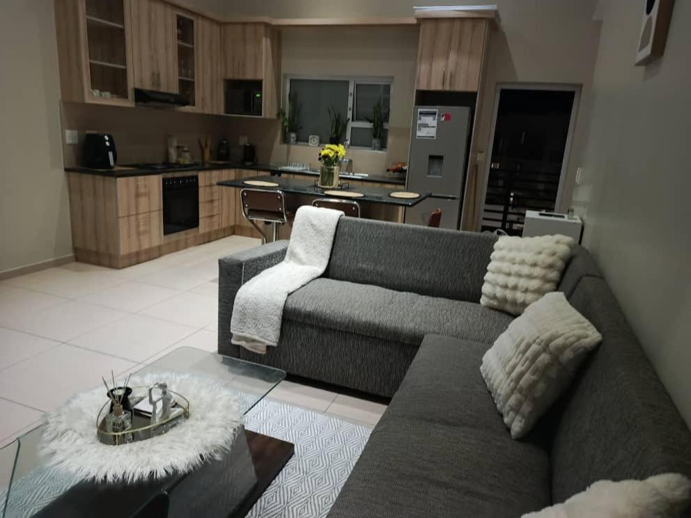 a living room with a couch and a kitchen at African Nest in Windhoek