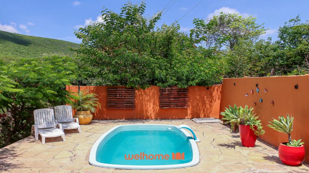 einen Pool in einem Garten mit zwei Stühlen und einem Zaun in der Unterkunft Suite Quadrupla em Rio Grande Com Piscina in Conceição do Gato