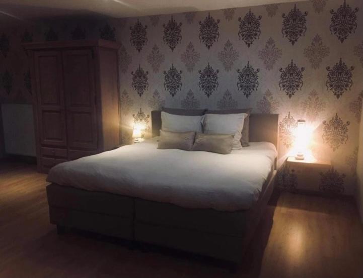 een slaapkamer met een groot wit bed met twee lampen bij La vie en Roos in Maldegem