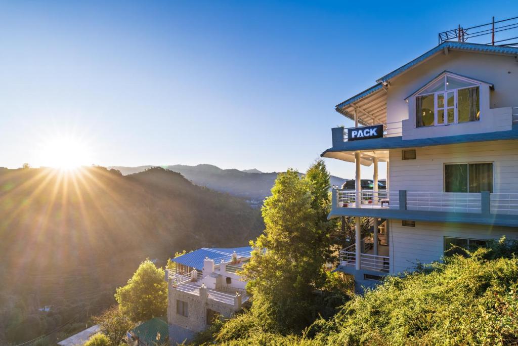 a hotel on top of a hill with the sun setting at PACK Mukteshwar in Mukteshwar