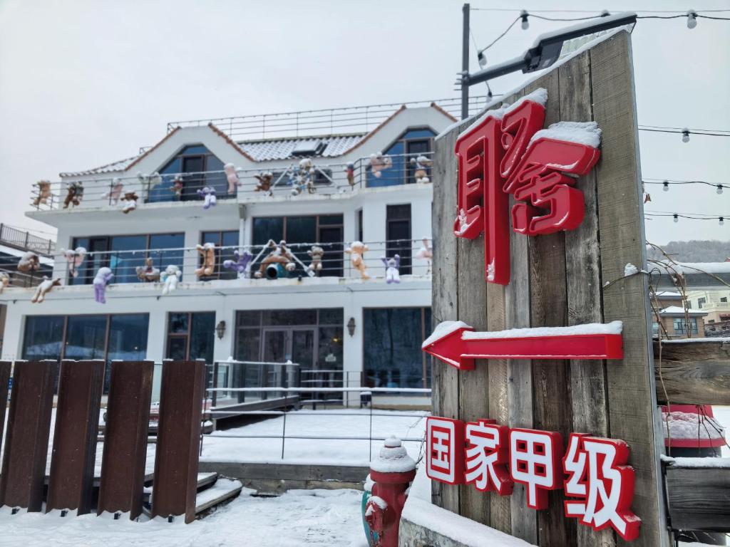 a building with a sign in the snow at Xiaozhu Bieyuan Resort Hotel in Shitouhezi