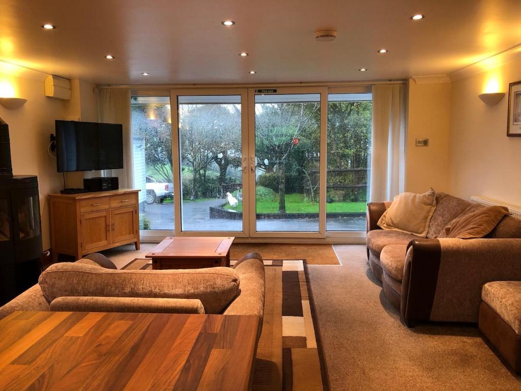 a living room with two couches and a tv at The Annexe at the Cedars in South Brent