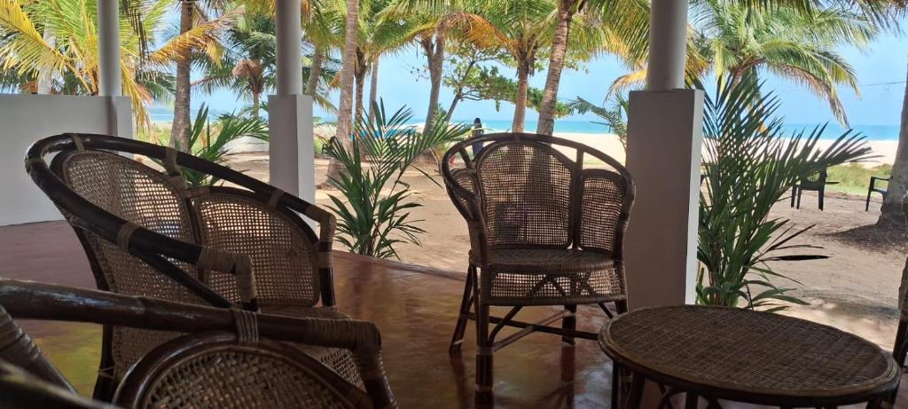 un groupe de chaises installées sur une véranda donnant sur la plage dans l'établissement Shalom Beach Villa, à Kalkudah