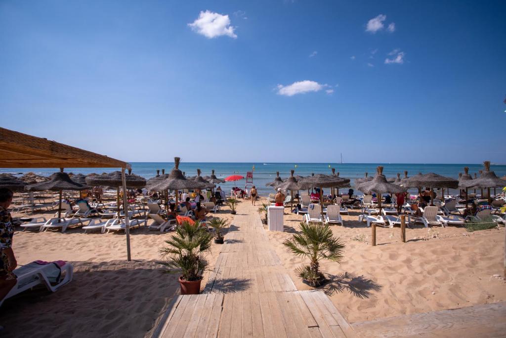a beach with chairs and umbrellas and the ocean at Hotel Baia Del Sole in Marina di Ragusa