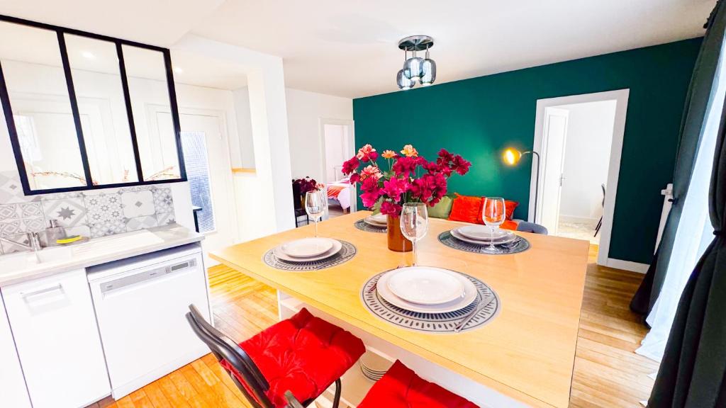 een keuken met een houten tafel en een vaas met bloemen bij La Petite Perle de Noisy in Noisy-le-Grand