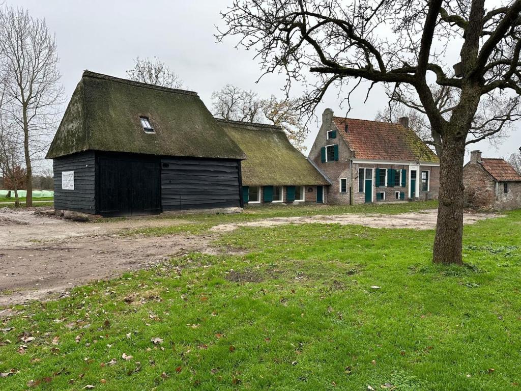 un vecchio fienile con un tetto verde e un albero di Bed and Breakfast Reestdal a Meppel