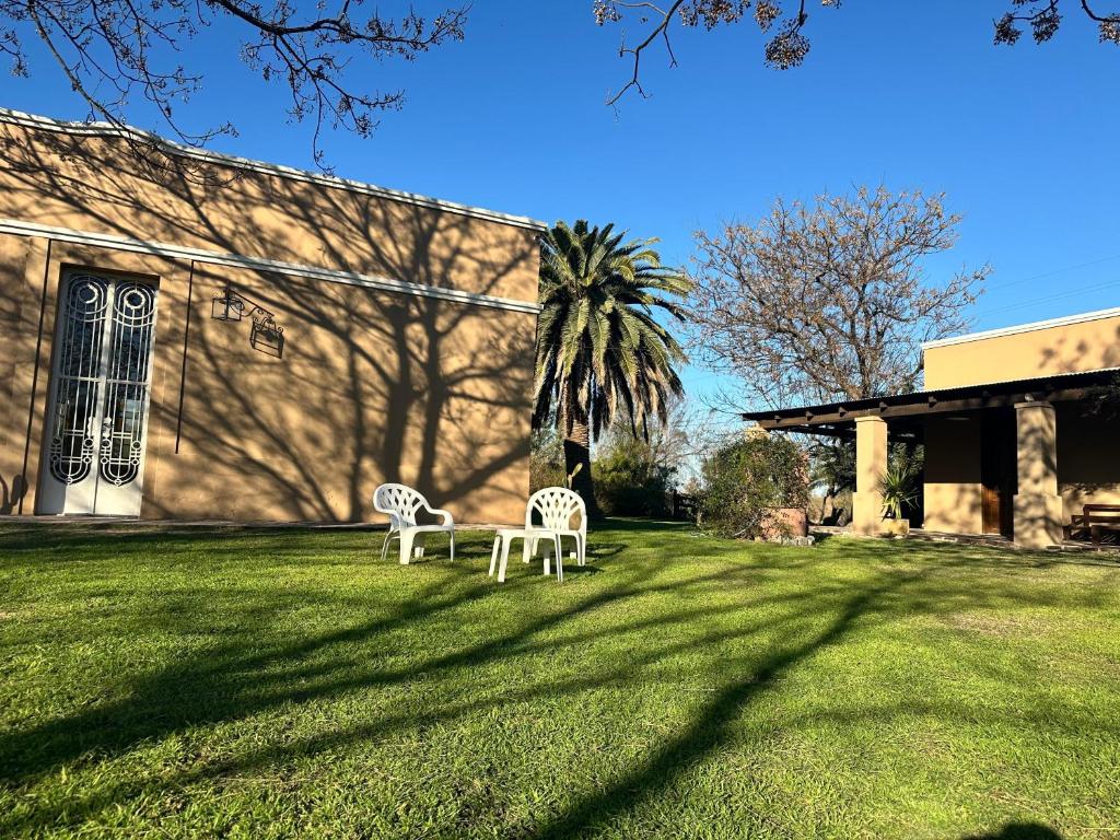 due sedie bianche sedute sull'erba di fronte a un edificio di Casa Casona Las Toscas a Miramar