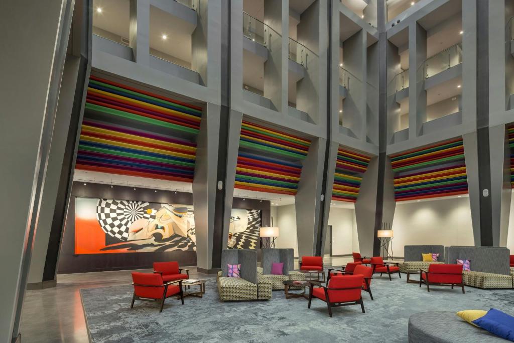 a lobby with red chairs and a colorful wall at The Summit Hotel in Cincinnati