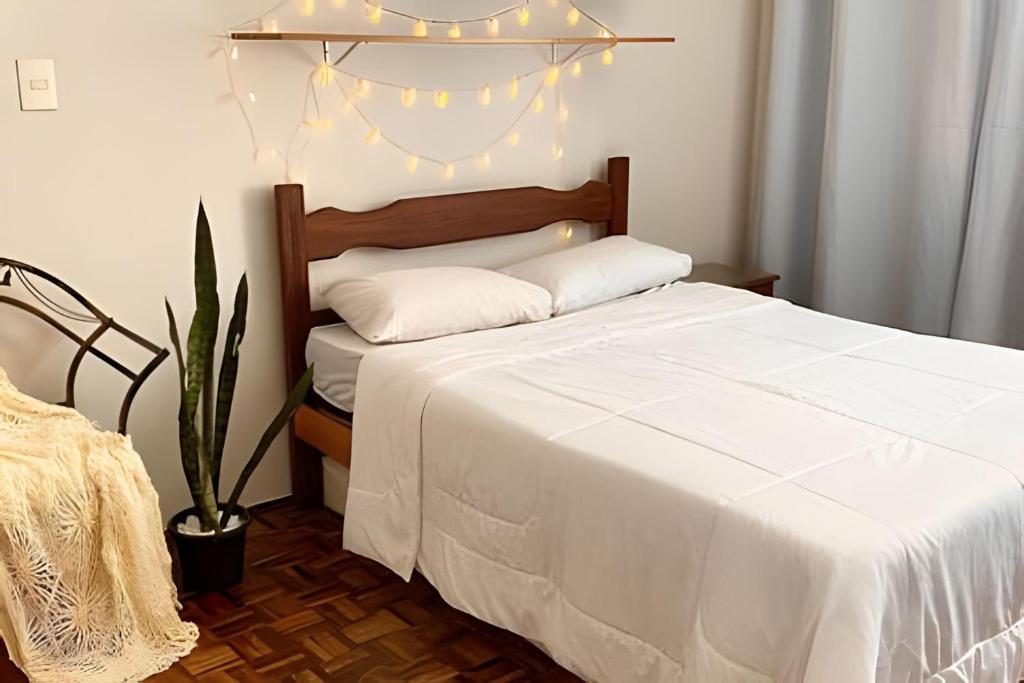 ein Schlafzimmer mit einem weißen Bett mit Lichtern darauf in der Unterkunft Kitnet na rua da UFV com Smart TV e Garagem in Viçosa