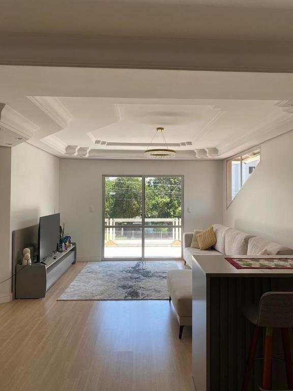 een woonkamer met een bank en een tv bij Apto centro de Ametista do Sul 2 dorm in Ametista do Sul