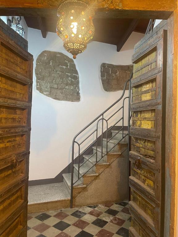a staircase in a room with a stone wall and a chandelier at Luxar Suites & Apartments in Assemini