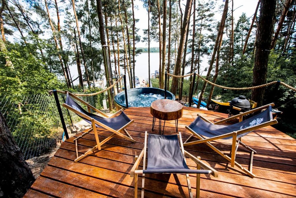 een houten terras met stoelen en een tafel en een zwembad bij Nad Narvią - Glamp in Serock