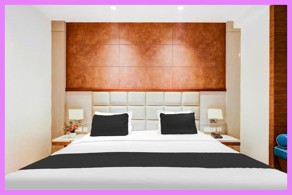 ein Schlafzimmer mit einem großen Bett mit einem hölzernen Kopfteil in der Unterkunft Hotel Kavira Palace Inn in Bhubaneshwar