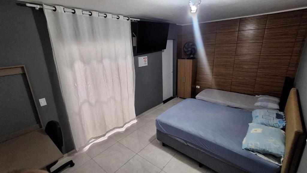 a bedroom with a blue bed and a window at Cintra Home Araçariguama - Casa 04 in Araçariguama