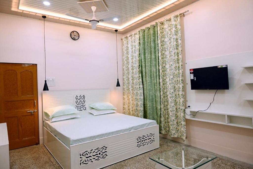 a bedroom with a white bed and a tv at Madhi Basera in Varanasi
