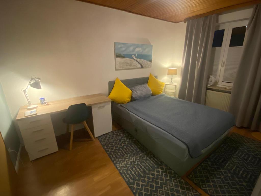 a bedroom with a bed with yellow pillows and a desk at Apartment am Waldrand in Itzehoe