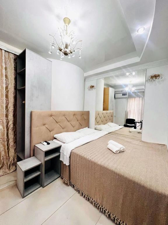 a bedroom with a large bed and a chandelier at CityCenter Studio in Chişinău