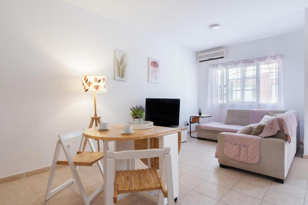 ein Wohnzimmer mit einem Tisch und einem Sofa in der Unterkunft Bungalow - Playa Maspalomas in San Bartolomé de Tirajana
