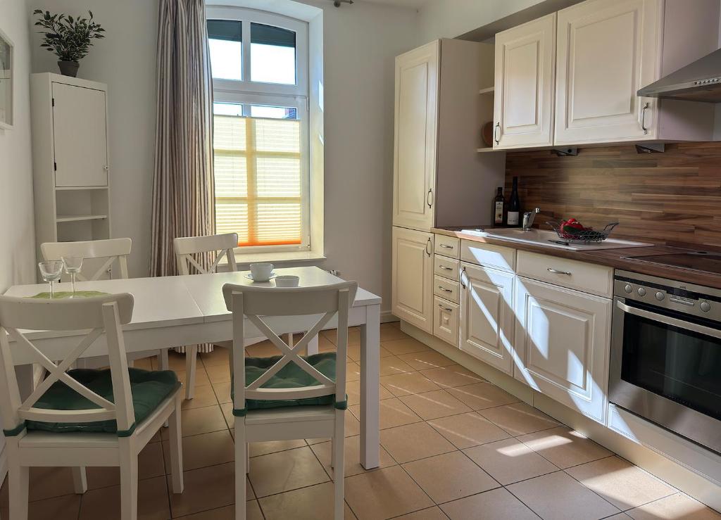 een keuken met witte kasten en een tafel en stoelen bij Ferienwohnung Medemspeicher in Otterndorf