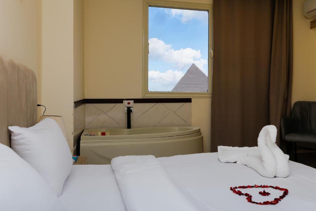 Mazaya Pyramids view inn في Banī Ghālib: غرفة فندق بها سرير ونافذة بها هرم