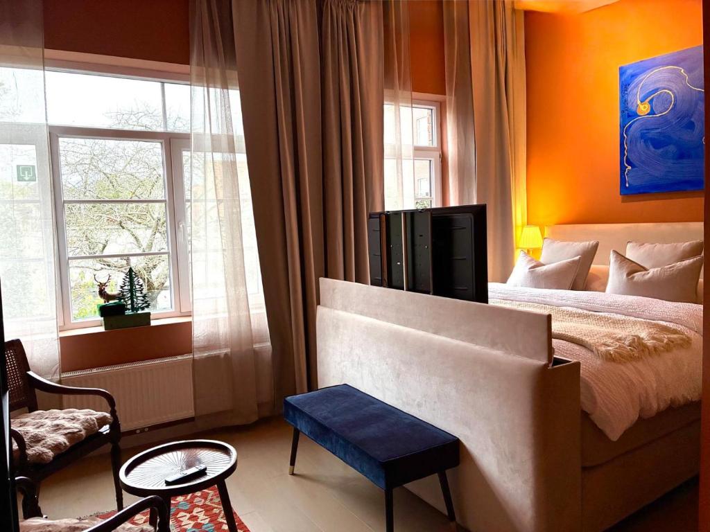 een slaapkamer met een bed, een stoel en ramen bij Si brugge in Brugge