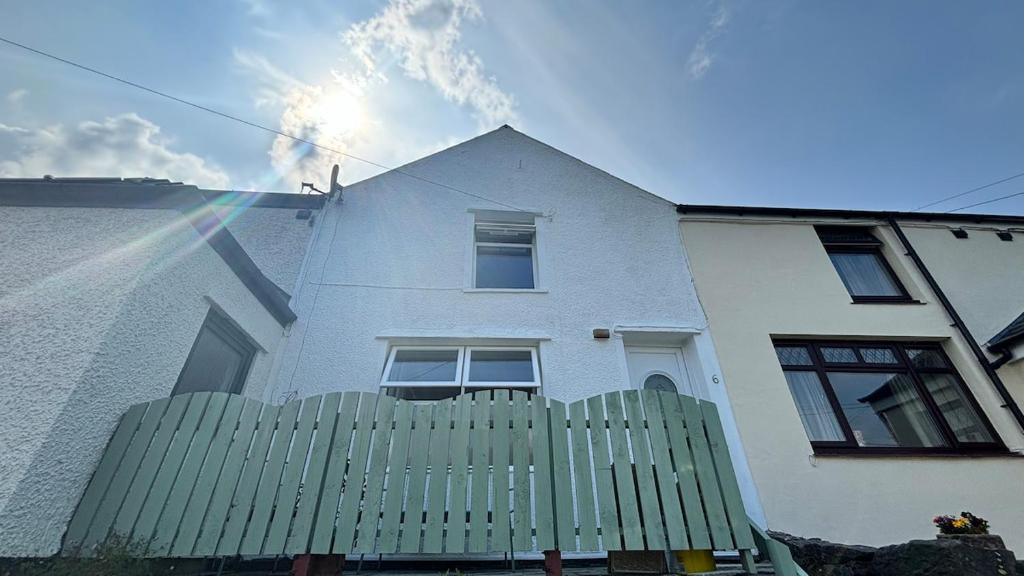 een wit huis met een groene schutting en een regenboog bij Cottage in Llanberis in Llanberis