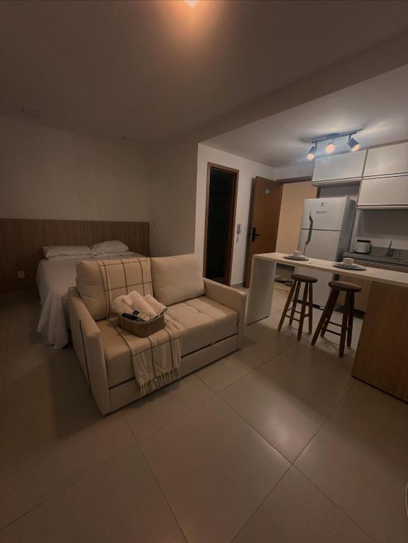 a living room with a couch and a bed and a kitchen at Studio On Mateus in Juiz de Fora