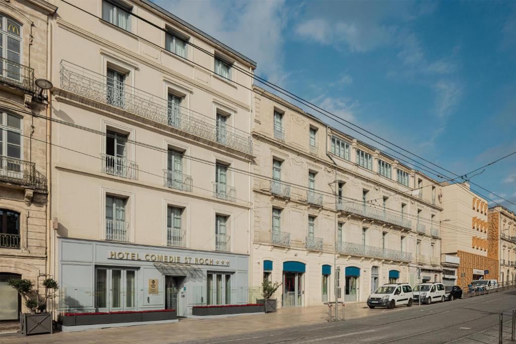 Un gran edificio blanco en una calle con coches aparcados en el exterior en Best Western Plus Comedie Saint Roch, en Montpellier